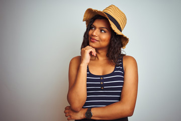 Beautiful transsexual transgender woman wearing summer hat over isolated white background with hand on chin thinking about question, pensive expression. Smiling with thoughtful face. Doubt concept.