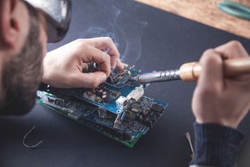 Computer hardware engineering. Engineer soldering computer motherboard