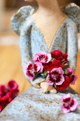 Ceramic figure of an angel holds a popular fragrant biennial garden plant, closeup.