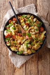 Appetizer of fried white cabbage with bacon closeup on a plate on a table. Vertical top view