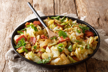 portion of fried cabbage with bacon closeup on a plate on a table. horizontal