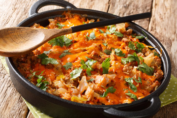 German cabbage casserole with ground beef, tomatoes, onions and cheddar cheese close-up in a pan. horizontal