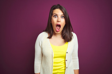 Young beautiful brunette woman a jacket over purple isolated background afraid and shocked with surprise expression, fear and excited face.
