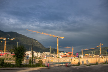 Baustelle mit Kränen nach Regen mit Bergen im Hintergrund