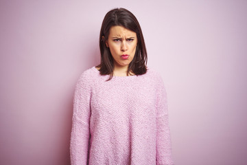Young beautiful brunette woman wearing a sweater over pink isolated background skeptic and nervous, frowning upset because of problem. Negative person.