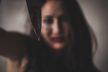 Close up bloody knife of horror female assassin with scary face on black background, Depression and...