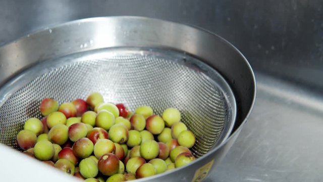 A Japanese female chef washing Japanese Ume (making UMEBOSHI) in the sink at home kitchen, Tokyo, Japan. May 2019. Camera fixed, Extreme close-up, high angle