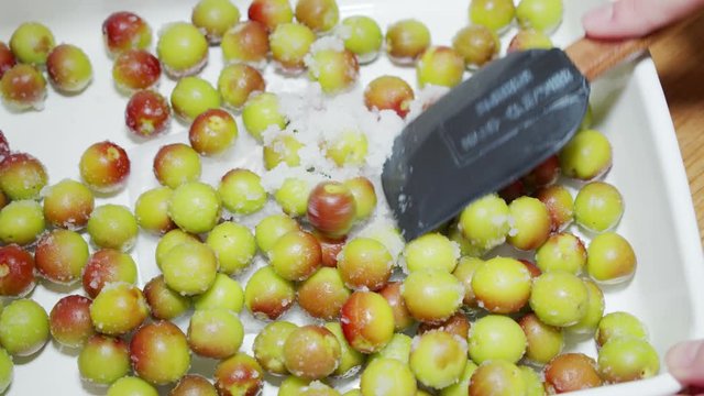 A Japanese female chef spreading Umeboshi (pickled Japanese Ume) in a food container at home kitchen, Tokyo, Japan. May 2019. Camera fixed, Extreme close-up, high angle