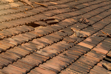 Obraz na płótnie Canvas Broken old terracotta rooftiles with hole, toned with sunlight. Close up. Textured summer background.