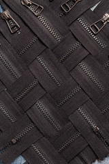 Pack a lot of black metal brass zippers stripes with sliders pattern for handmade sewing tailoring leatherwork leathercraft on the blue wooden background