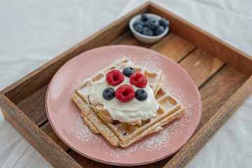 Tasty Belgian waffles with clotted cream and berries on plate