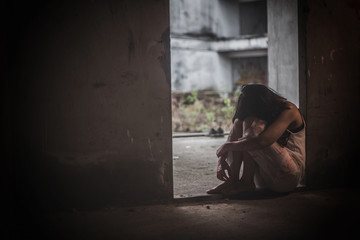 Depression, Depressed woman sitting alone in the dark room with a low light environment.