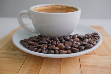 white cup and coffee bean on wood block