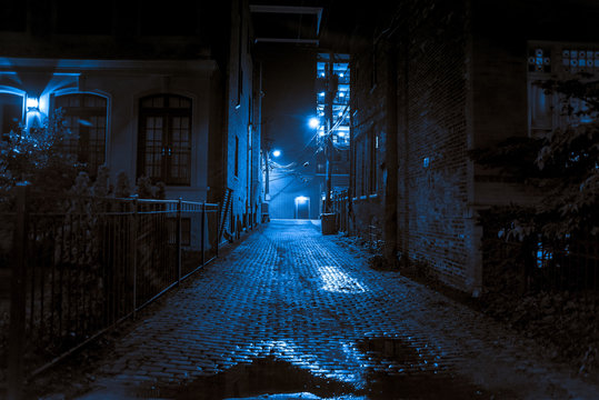 Dark and scary vintage cobblestone brick city alley at night in Chicago