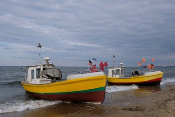 Wooden fishing boats on the beach of Baltic Sea in Sopot/Poland. Red flag poles for marking networks.