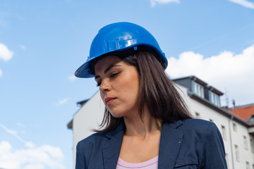 Close up profile portrait of a female engineer wearing a blue protective helmet