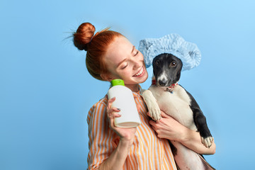ginger girl enjoying washing the dog with foam and water.close up portrait, isolated blue background, studio shot, happiness, lifestyle, spare time