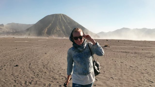 Happy woman traveler walking in a volcanic dusty desert near beautiful Mount Bromo in East Java, Indonesia