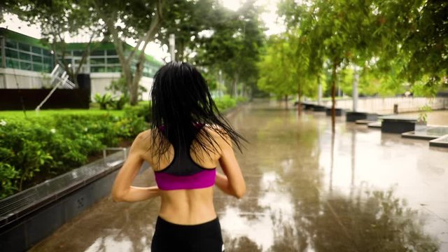 Middle-aged Asian woman jogging in the rain in Singapore