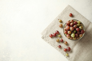 Red and green gooseberries, ripe berries on table in plate.