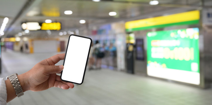 Young Man Holding Blank Screen Smartphone At Railway Station