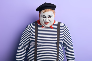 talented clown putting tongue out, trying to make children laughing, happy. close up portrait, studio shot. hungry fat clown licking his lips
