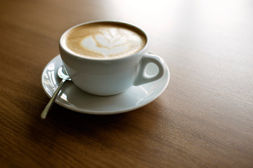 Cup of hot cappucino on the wooden table. Early morning breakfast