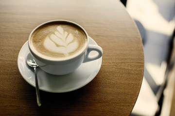 Cup of hot cappucino on the wooden table. Early morning breakfast