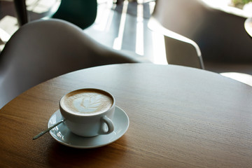 Cup of hot cappucino on the wooden table. Early morning breakfast