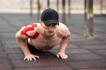Young European athlete with injury is training outdoors. Kinesiology ( therapeutic, Kinesio,...