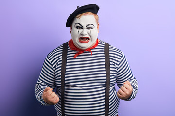 frustrated nervous mime with raised arms shouting, screaming, isolated blue background, studio shot. frustration, cruelty