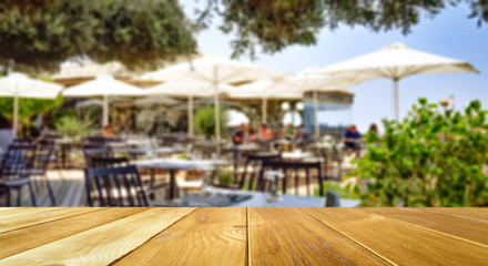 Table background and restaurant outside on sunny day in distance. Empty space for products and...
