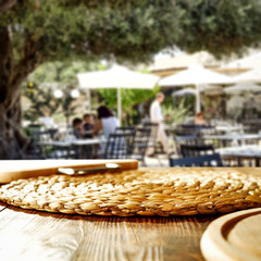 Table background and restaurant outside on sunny day in distance. Empty space for products and decoration.