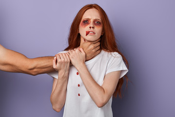 scared woman trying to stop her angry husband who wants to kill her. closeup portrait, studio shot,...