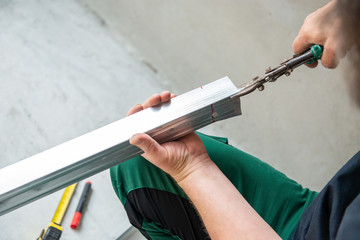 Male worker works with profile for drywall, marker marks for cutting. Construction work, repair. Renovation