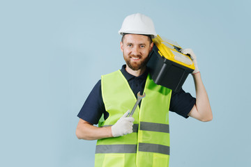 Construction worker with tool case in a white helmet and yellow safety vest