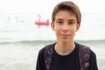 Handsome young boy at beach in Alicante. Beautiful calm smiling teen boy at Mediterranean sea coast in Spain. Travel, summer vacation, tourism, teenage lifestyle.