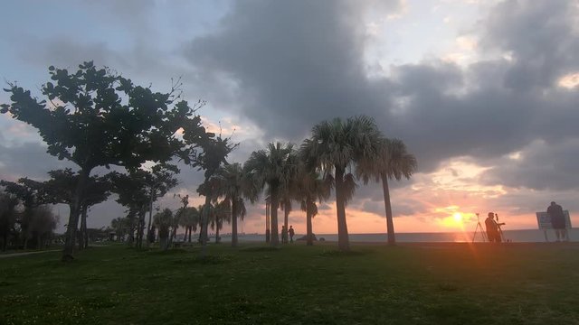 Time Lapse of palm trees and clouds moving in different directions. Sunset at Araha Beach, Okinawa, Japan