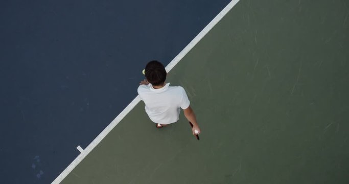 OVERHEAD CRANE Young Caucasian teenager male tennis player serving during a game or practice. Slow motion, 4K UHD RAW graded footage