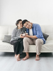 Happy Asian man giving gift box to his mother for Mother's Day celebration.