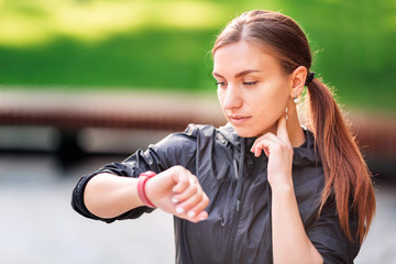 Beautiful sportive girl checking her pulse during fitness exercises, jogging