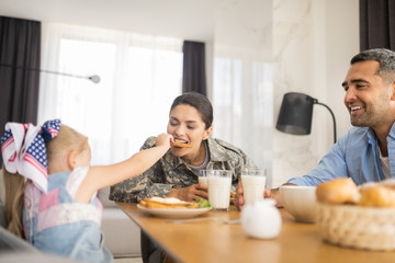Daughter sharing cookie with mother having family breakfast