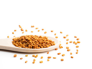 Wooden (Trigonella) spoon with fenugreek on a white background