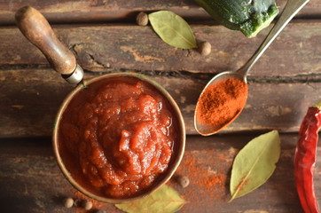 Ketchup with zucchini on a wooden background