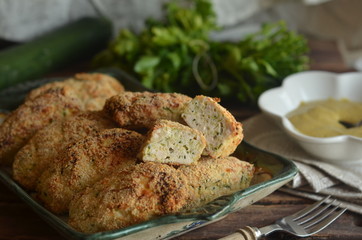 Homemade chicken croquettes with zucchini on a rustic dish on a wooden background