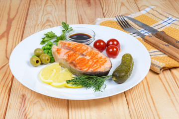 Grilled piece of arctic char among vegetables, greens and seasoning