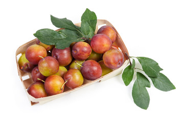 Top view of fresh plums with leaves in wooden basket