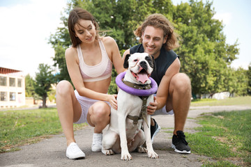 Sporty young couple with cute dog in park