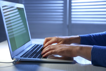 Woman using laptop at night, closeup