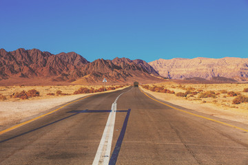 Driving a car on the mountain road in Israel. Desert landscape. Empty road. View from the car of mountain landscape on a sunny day with a clear blue sky. Israel